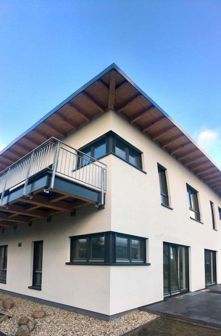 Haus mit sichtbaren Holzbauteilen am Dach und Balkon
